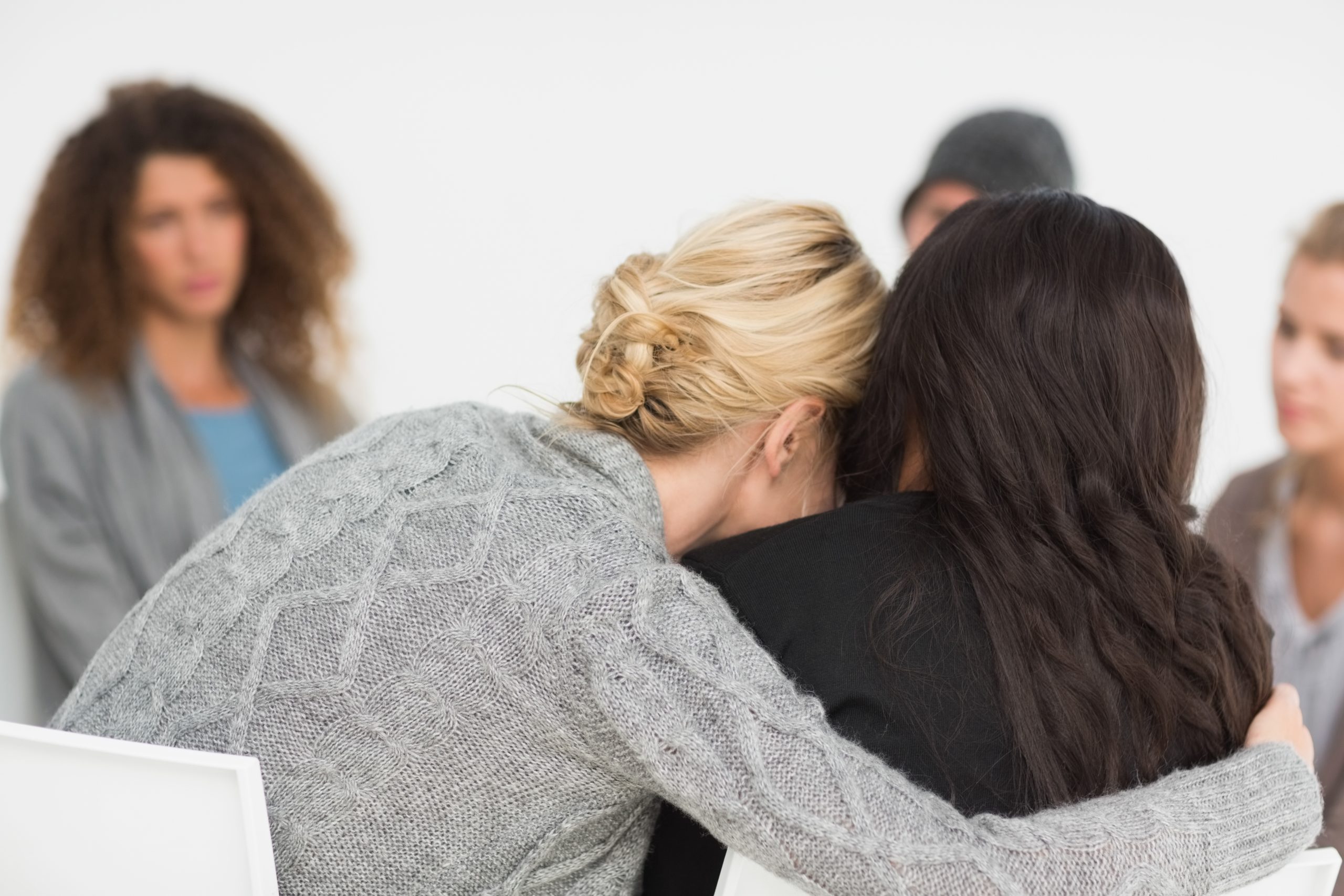 Women embracing in rehab group at therapy