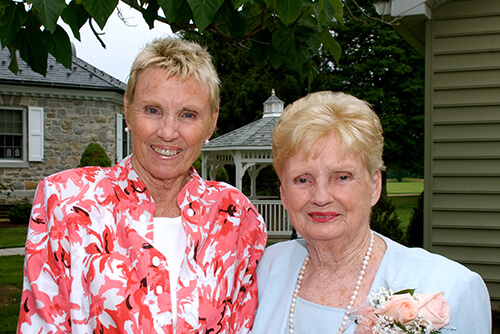 Two women with short blonde hair smile into camera.