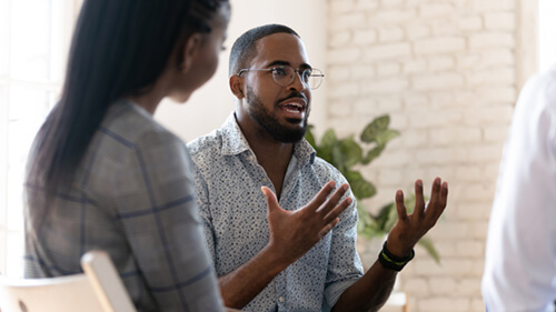 A man talks with his hand and a woman listens.