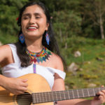 Woman playing instrument outdoors. music in nature, under a tree. musical interpretation on guitar. indigenous communities of the world. cultural diversity, Latin American population