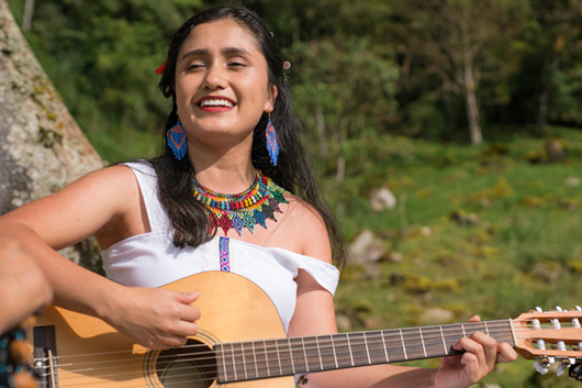Woman playing instrument outdoors. music in nature, under a tree. musical interpretation on guitar. indigenous communities of the world. cultural diversity, Latin American population