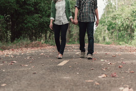 Young couple holding hands and walking through pathway on the street.