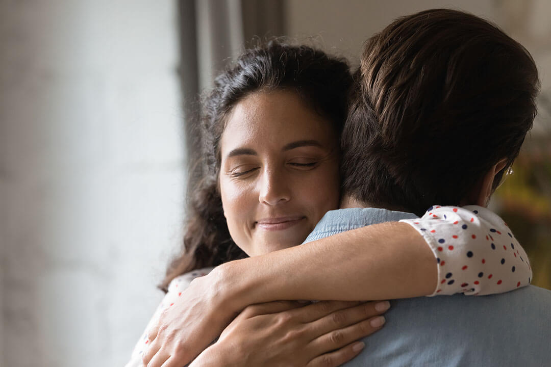 Close up smiling loving wife with closed eyes hugging husband, family, spouses enjoying tender moment, standing at home, happy attractive girlfriend and boyfriend embracing, romantic relationship