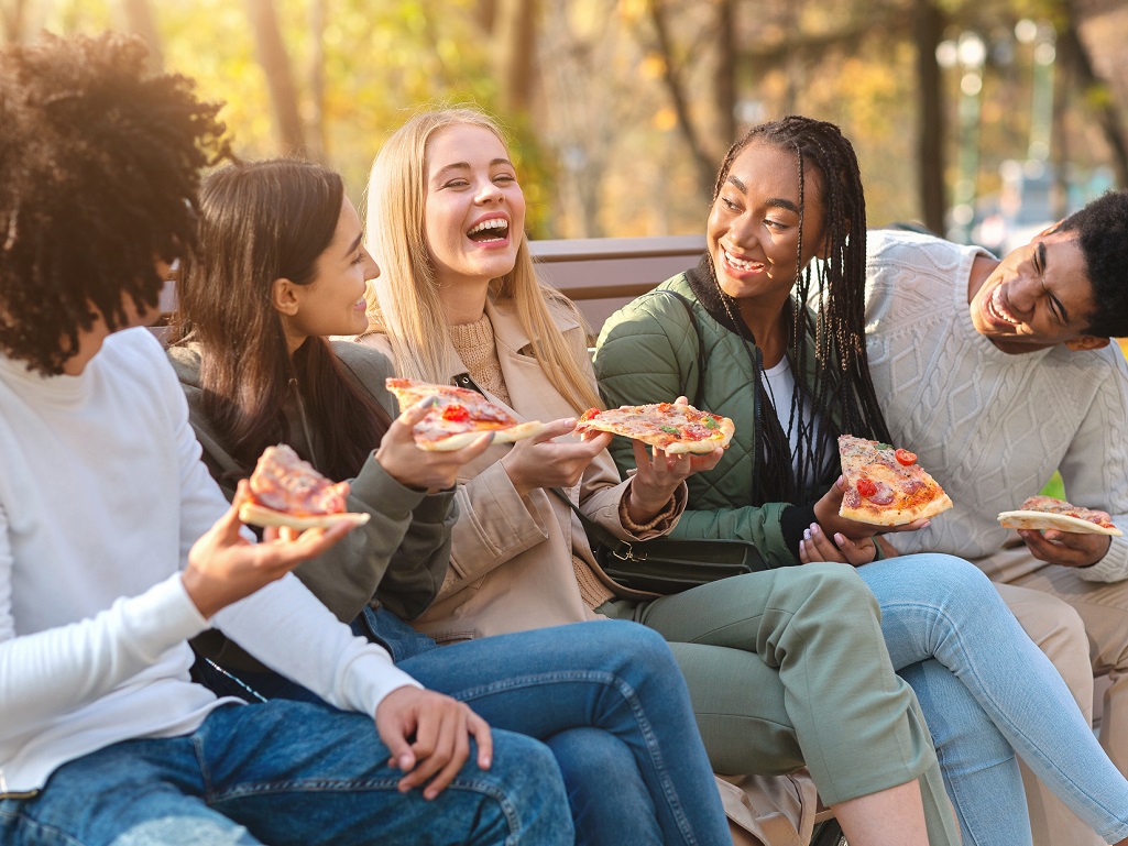 Group of teens eating pizza and laughing