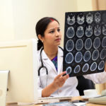 Young traditional female doctor examine brain x-ray picture