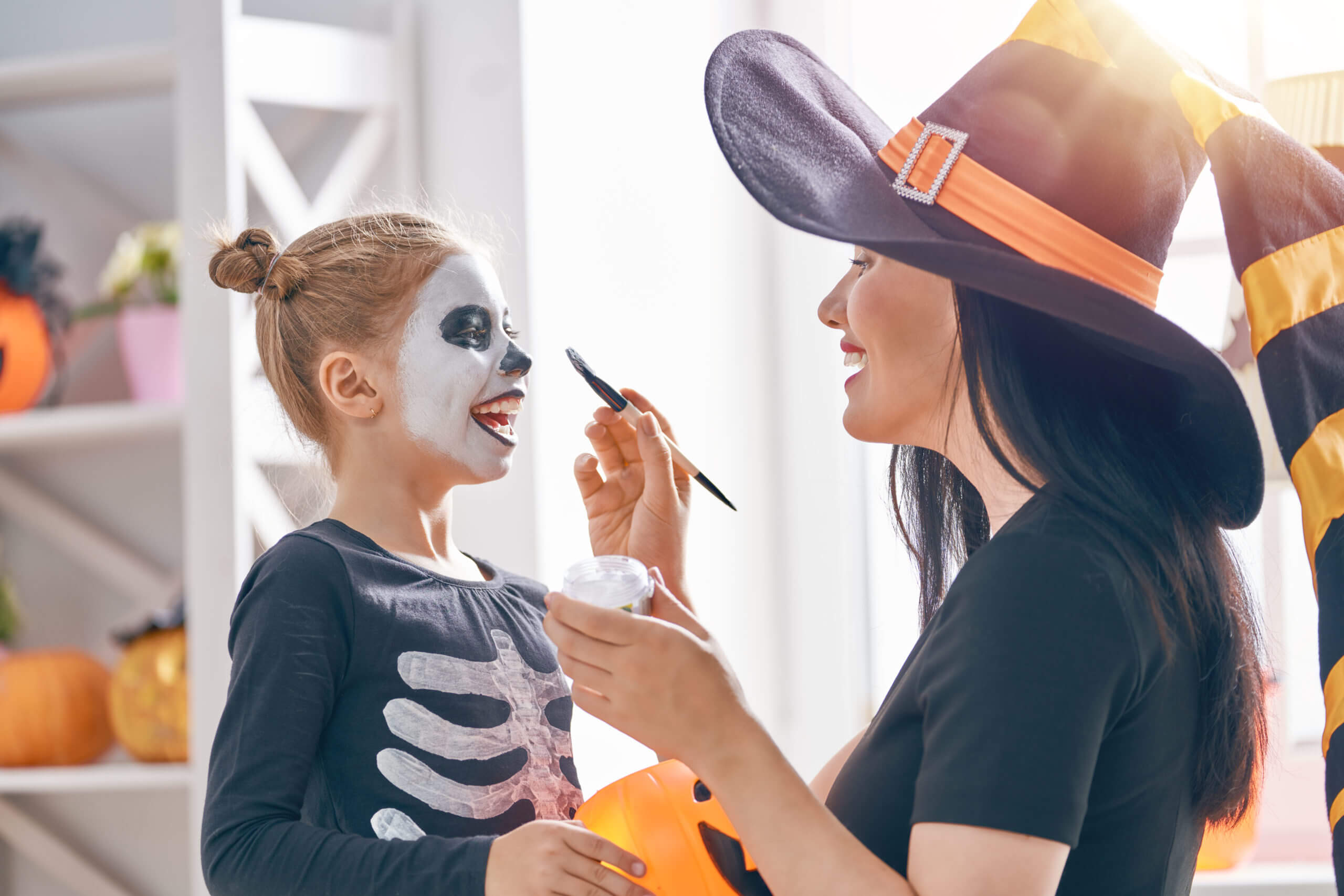 Happy family preparing for Halloween! Young mom and her kid in carnival costumes celebrate the holidays.