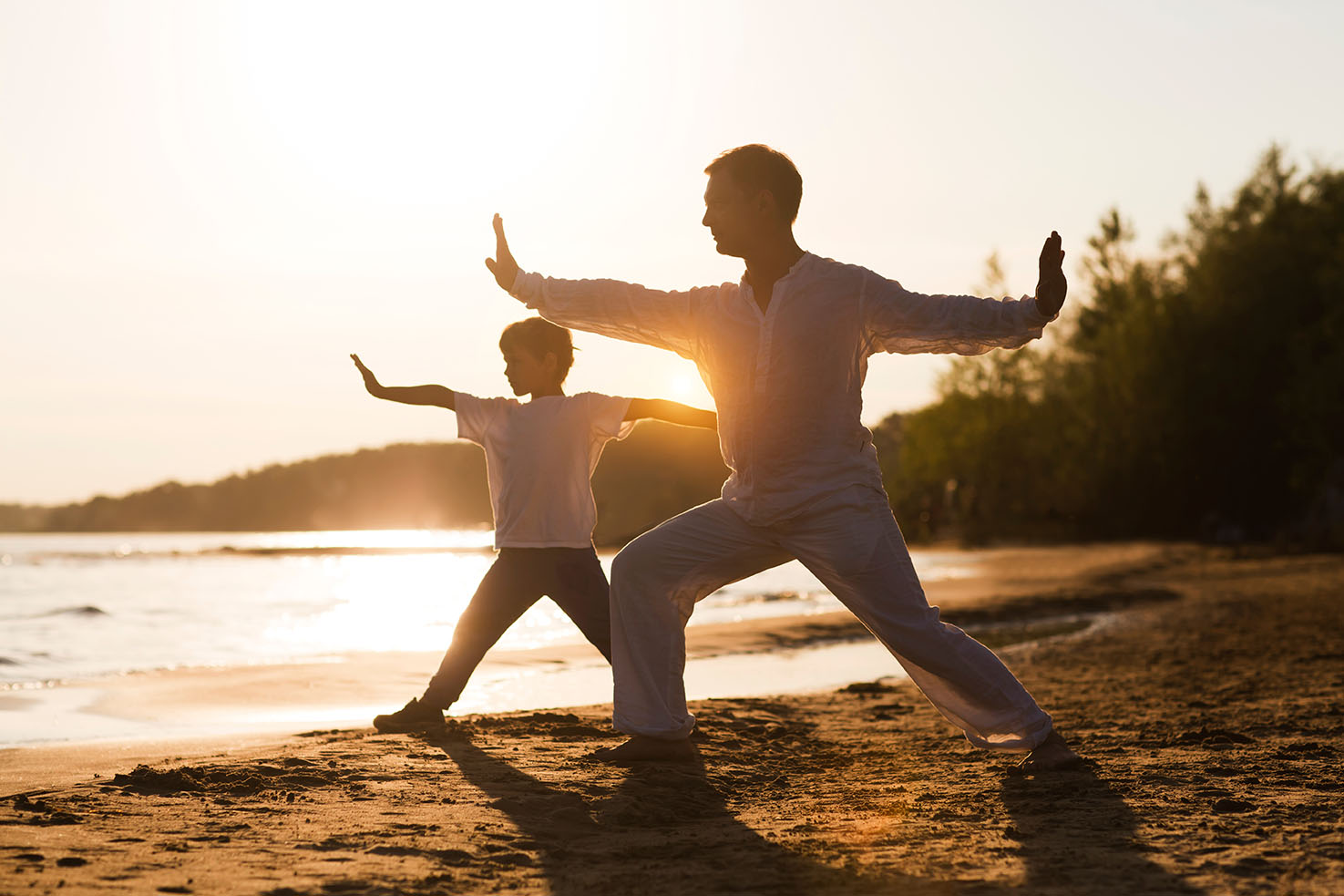 Family dad and little son practice Tai Chi Chuan in the summer on the beach. solo outdoor activities. Social Distancing. family exercising together. Simple living